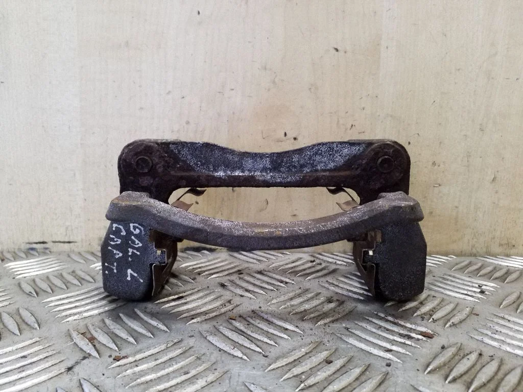 Bremžu klučiņu turētājs (aizmugurē) – kreisā